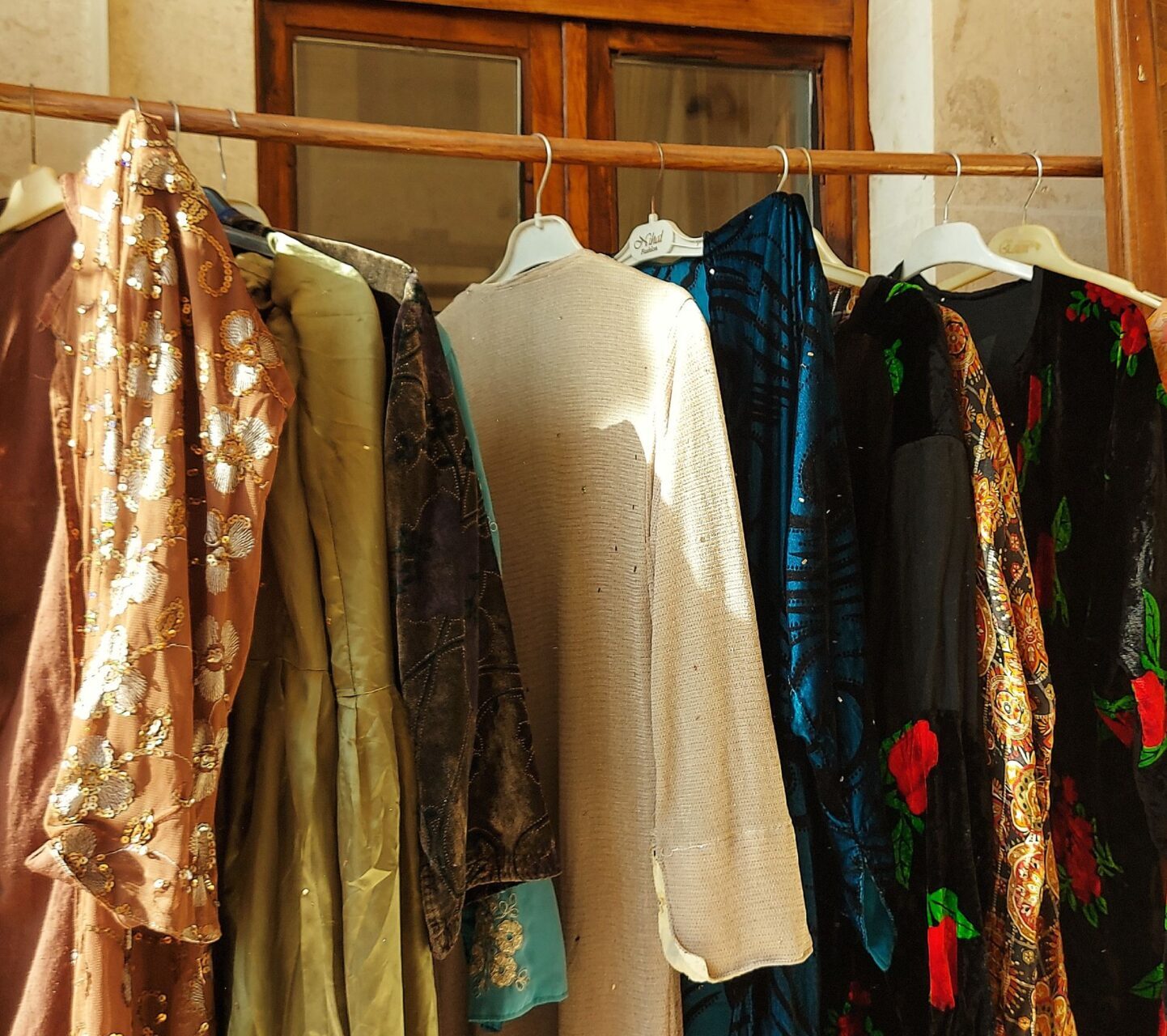 Abayas in different colours and styles hanging on a rail in warm sunlight – BaayWears exclusive modest collection
